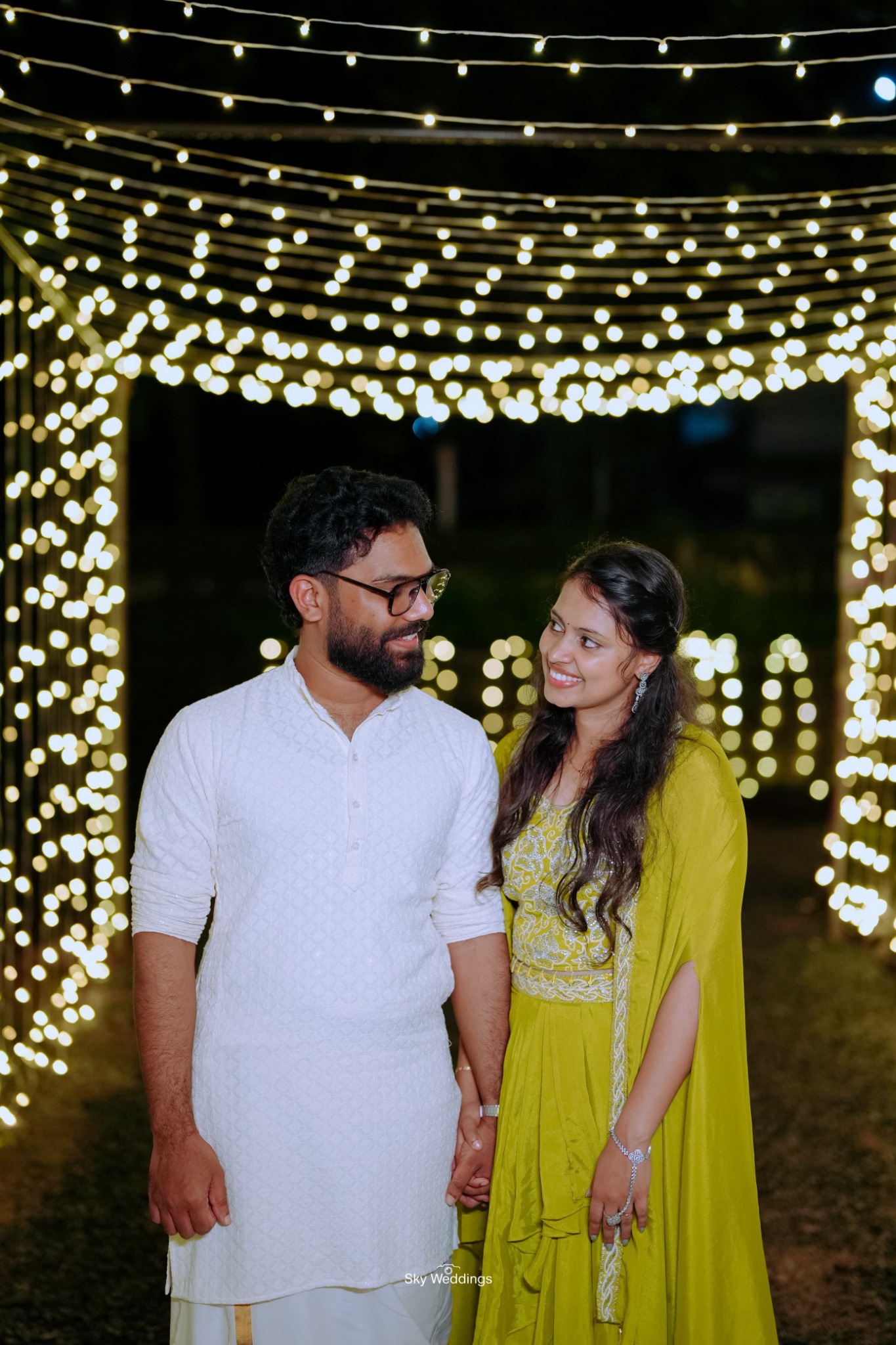 Smiling under a canopy of twinkling lights