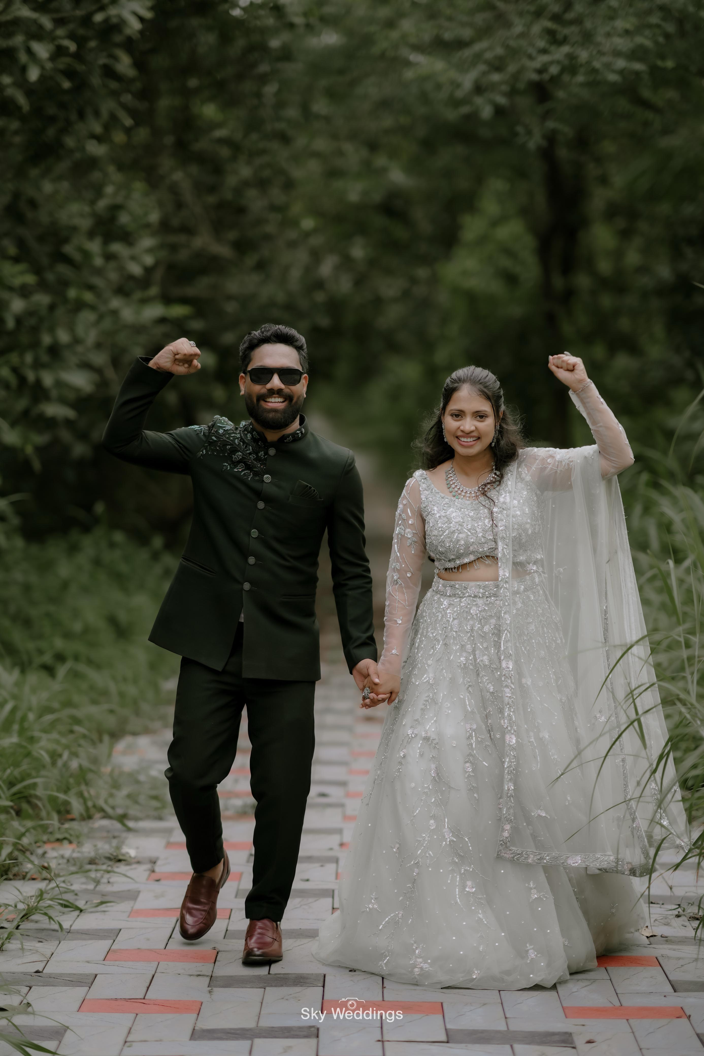 Jithin and Binju smiling beside a stone wall
